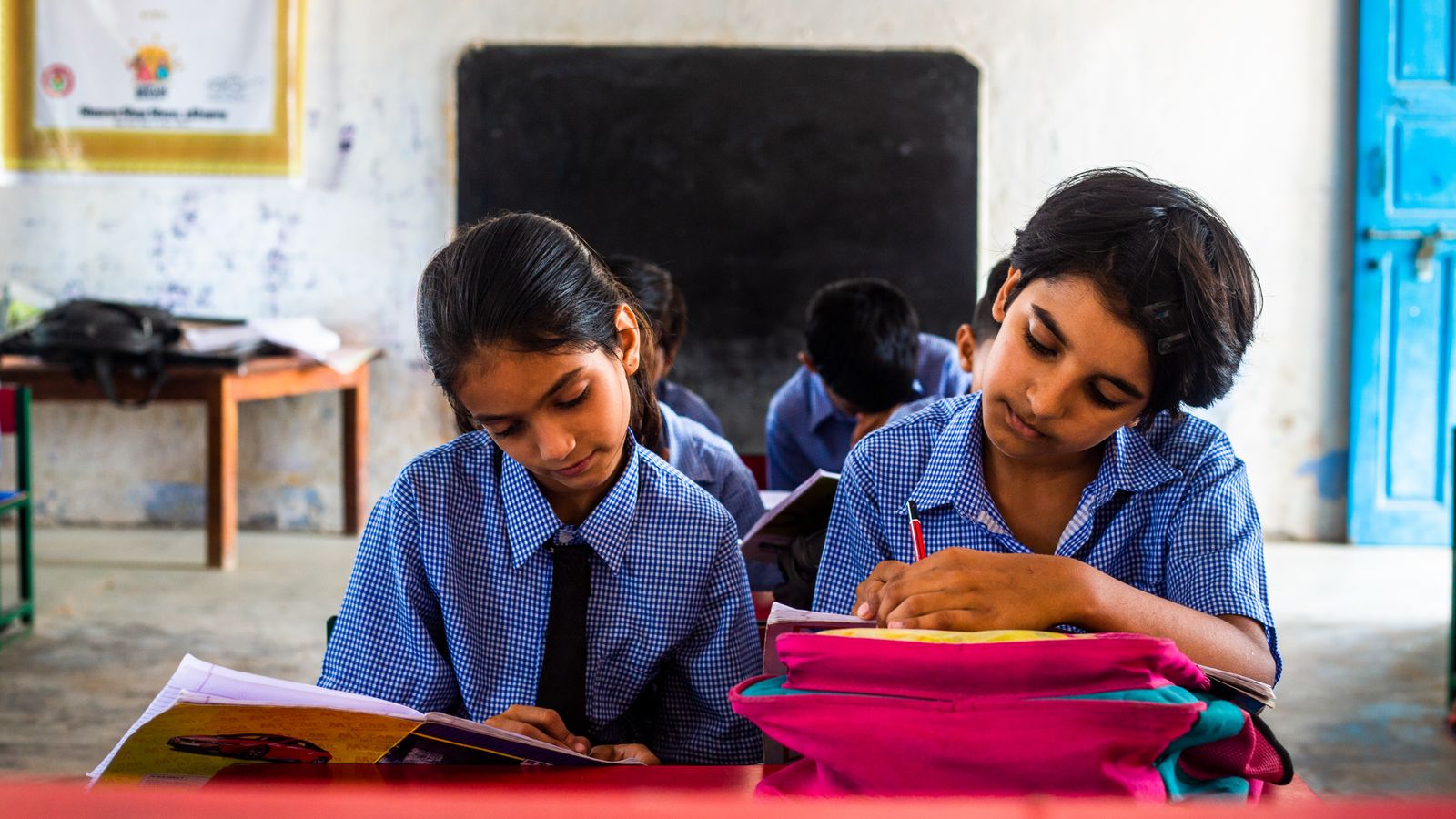 Two children in school uniforms studying together at a classroom desk