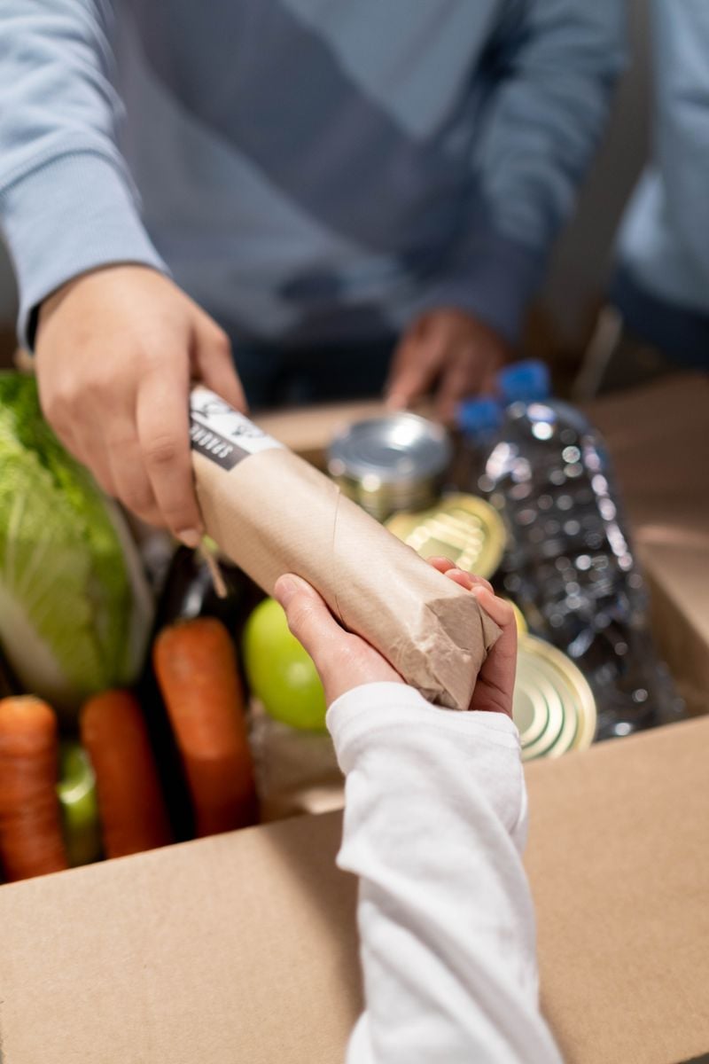 A volunteer handing over a box of groceries for community support